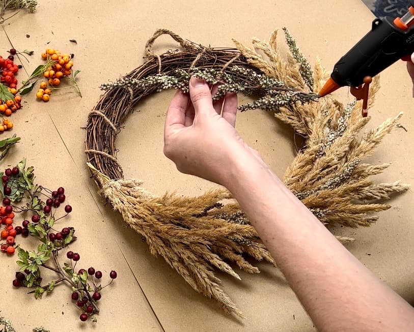 using glue gun to attach flowers to flower wreath diy