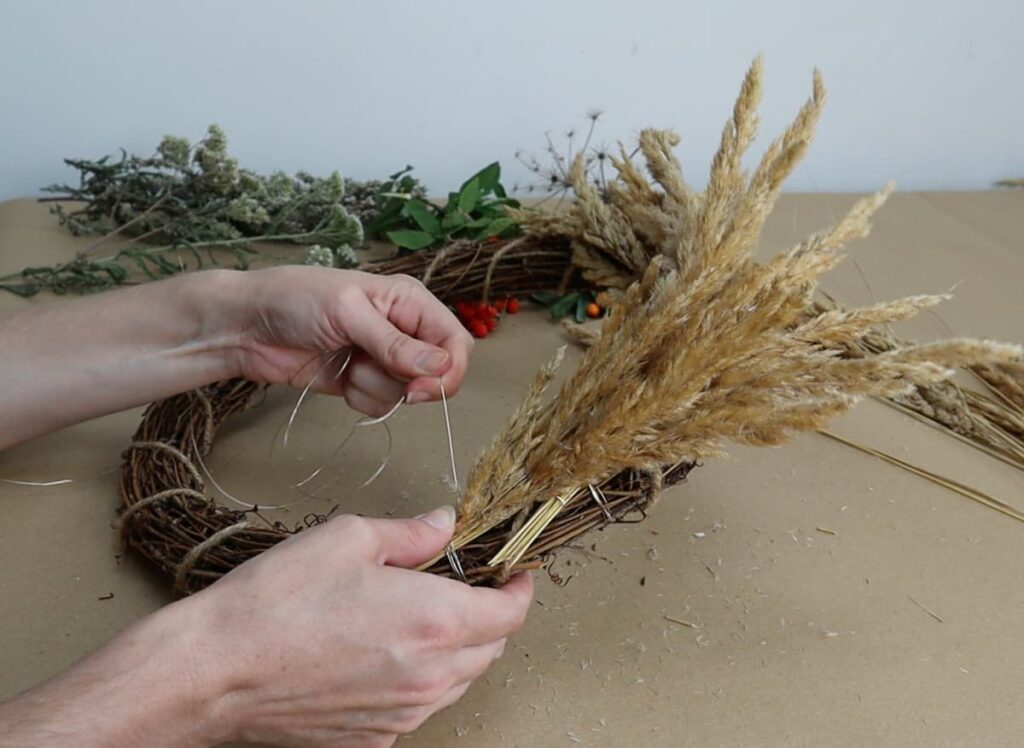 attaching flowers to wreath base with wire