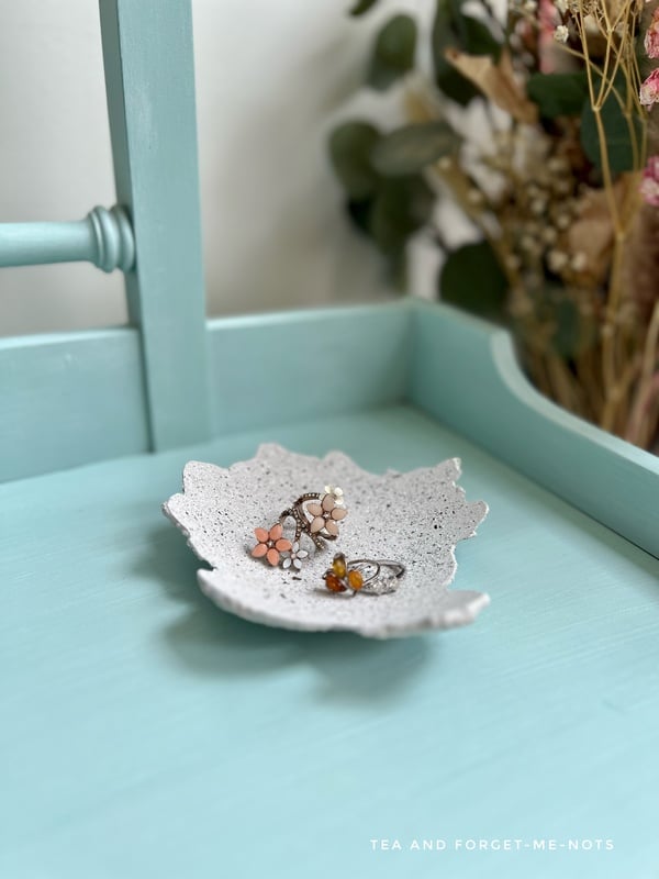 image shows a stone effect diy concrete bowl trinket dish on a blue table.