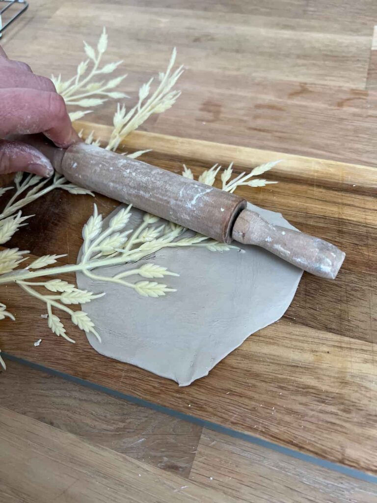 rolling a flower stamp into clay