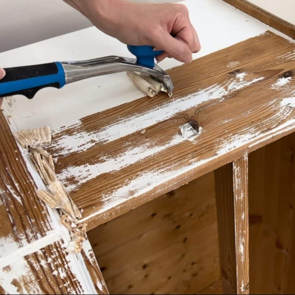 using a carbide scraper to remove paint from wood.