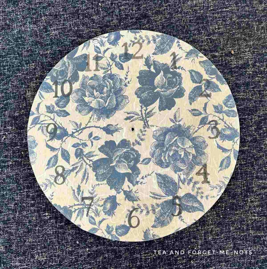 Stenciled clock face over decoupage paper