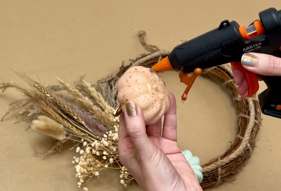 gluing faux pumpkin to diy wreath