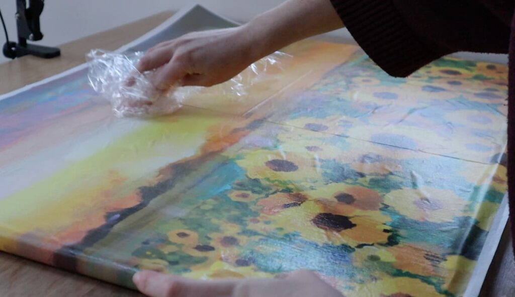 image shows smoothing out decoupage paper with plastic wrap.