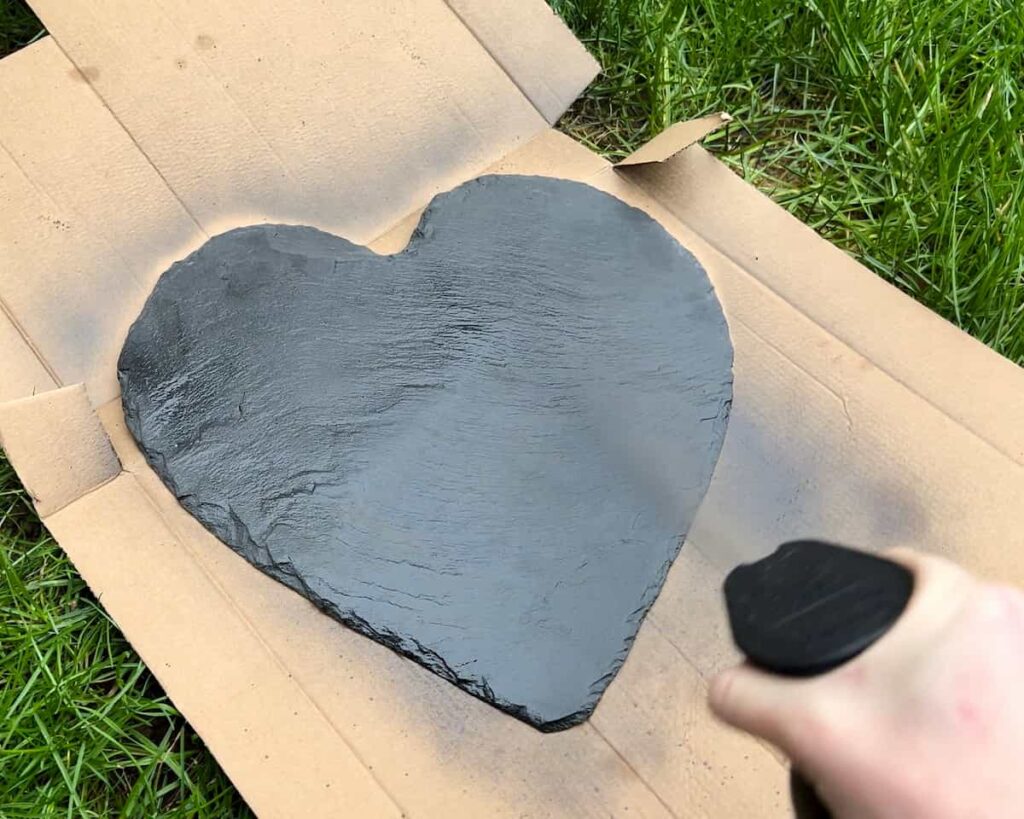 image shows spray painting slate with black paint.
