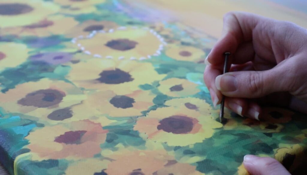 image shows creating holes with a nail to embroider on canvas.