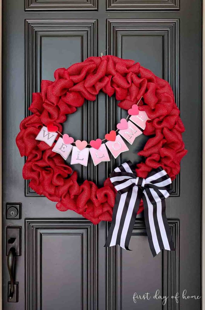 image shows red wreath made from burlap with black and white bow.