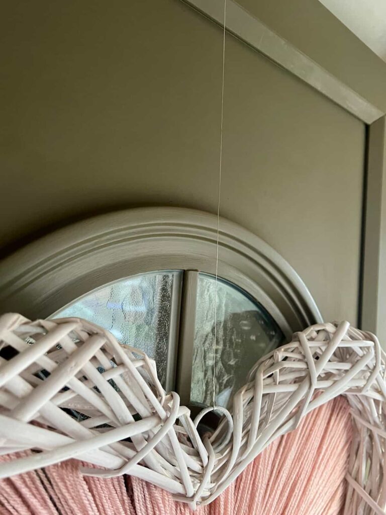 Image shows wreath hung on front door with wire.