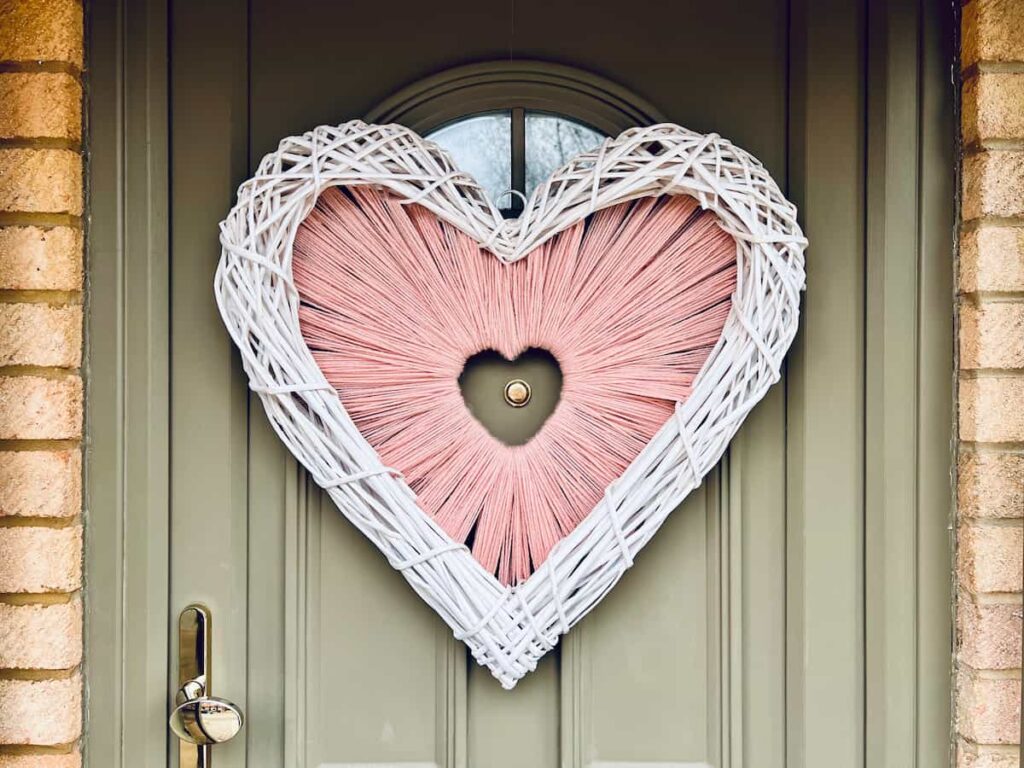 Image shows heart shaped wreath on green front door.