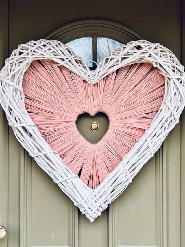 Image shows heart shaped wreath on green front door.