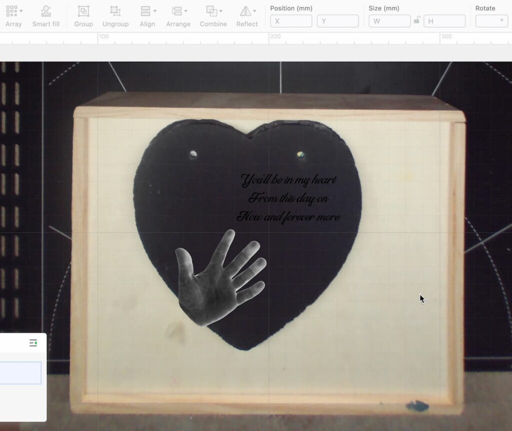 image shows slate heart in laser machine with image of hand and writing on top.