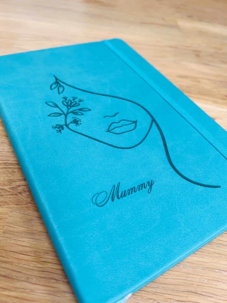 image shows engraved notebook with woman's face and the word mummy.