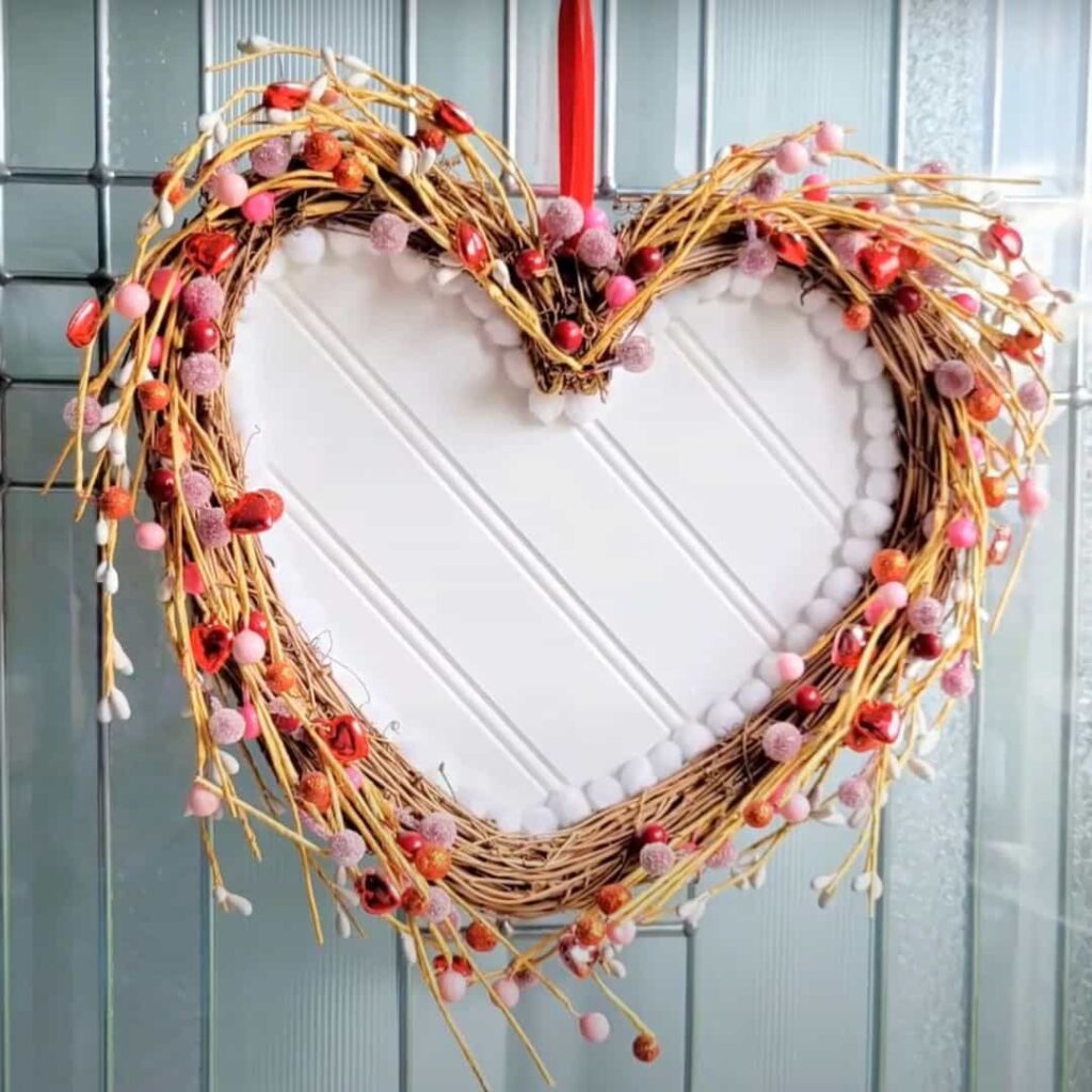 image shows heart wreath decorated with white beadboard.