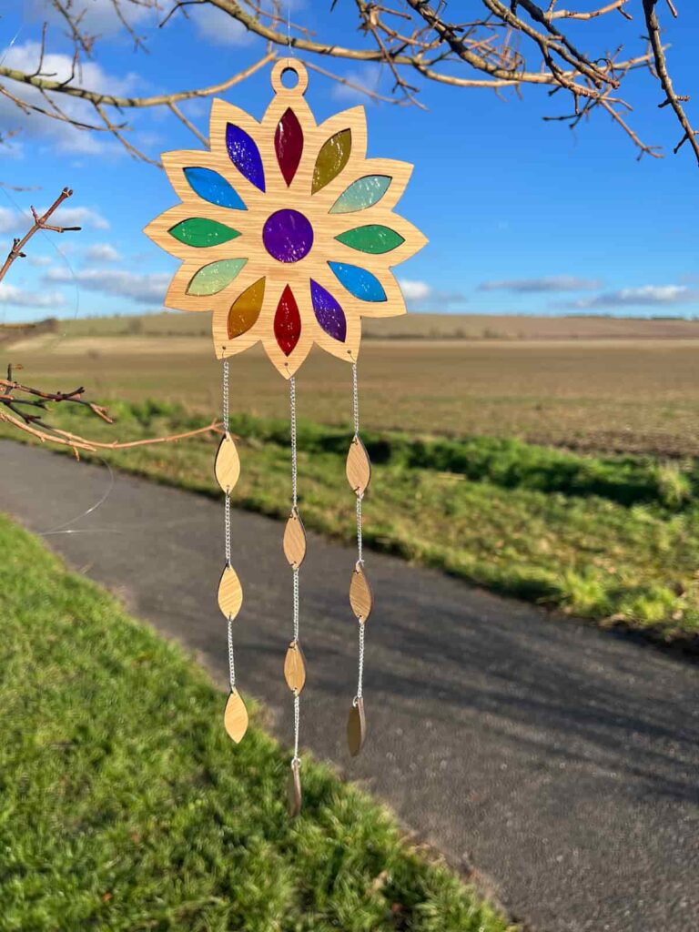 diy suncatcher hanging from a tree in front of a field.