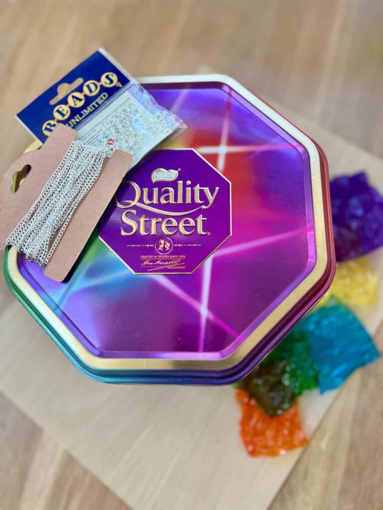 image shows a quality street tin, silver chains and jump rings.