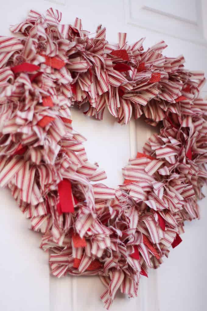 image shows heart shaped wreath covered with white and red striped fabric.