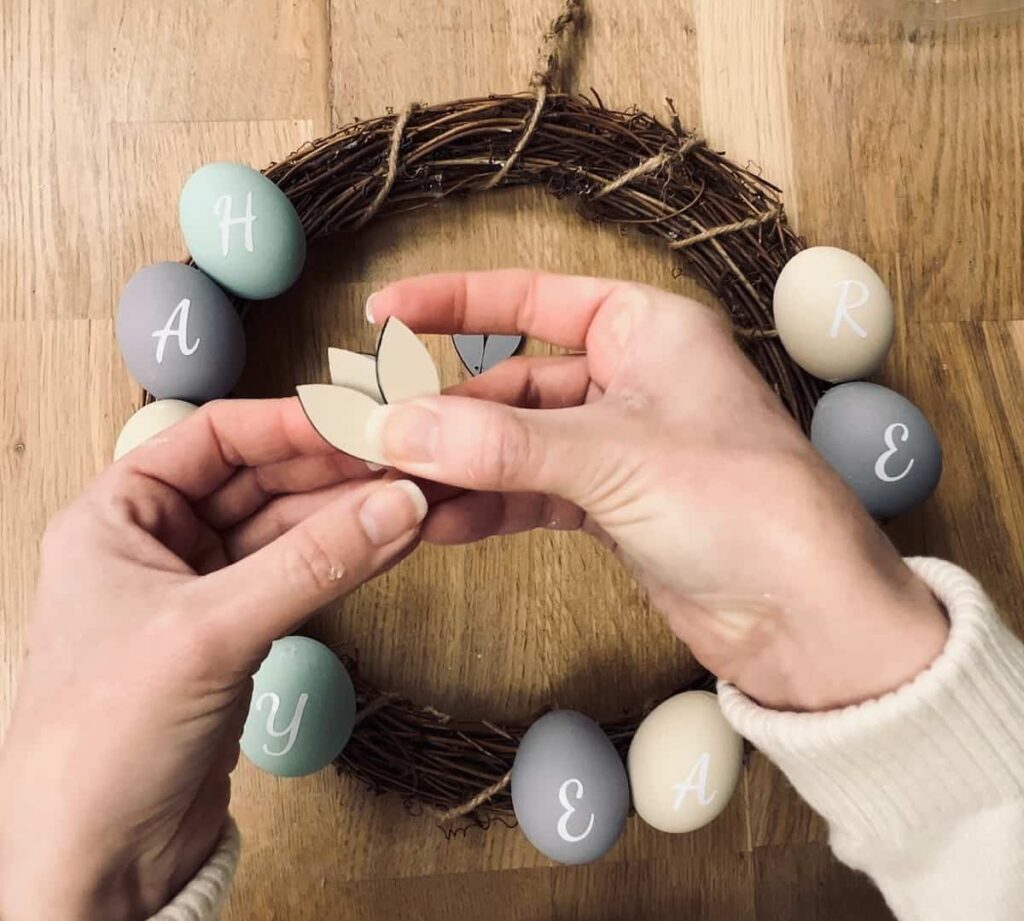 image shows adding painted scrap wood as decoration to the easter wreath.