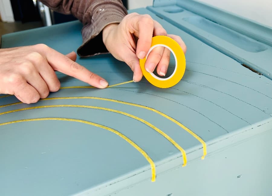image shows applying tape over rainbow lines on desk.