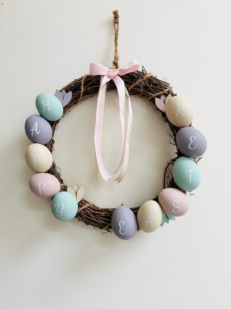 image shows easter egg wreath on a white wall.