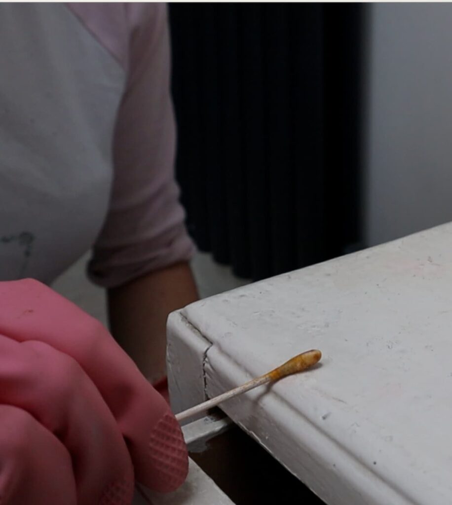 image shows using a swab to test for lead paint on a chest of drawers.