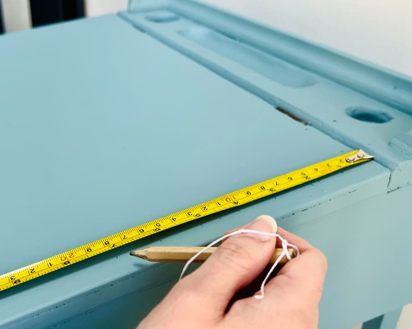 image shows using a measuring tape to mark lines on a desk.