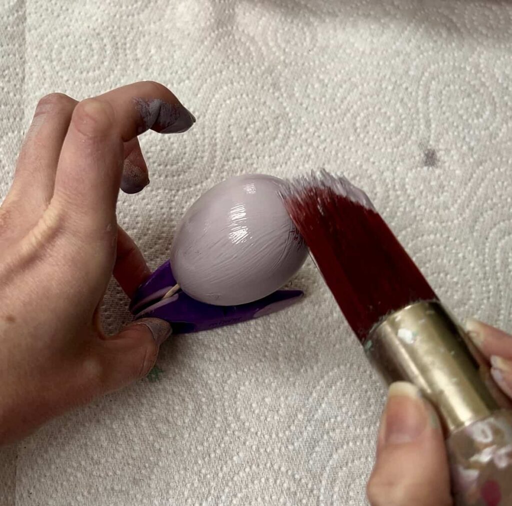 image shows painting an egg with purple paint.