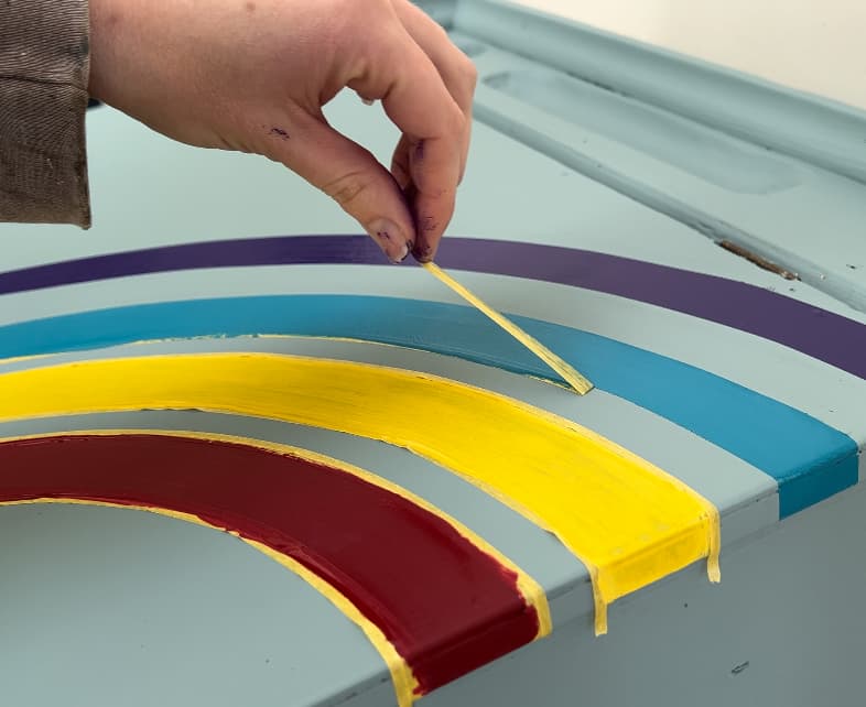 image shows peeling the tape off of a painted rainbow.