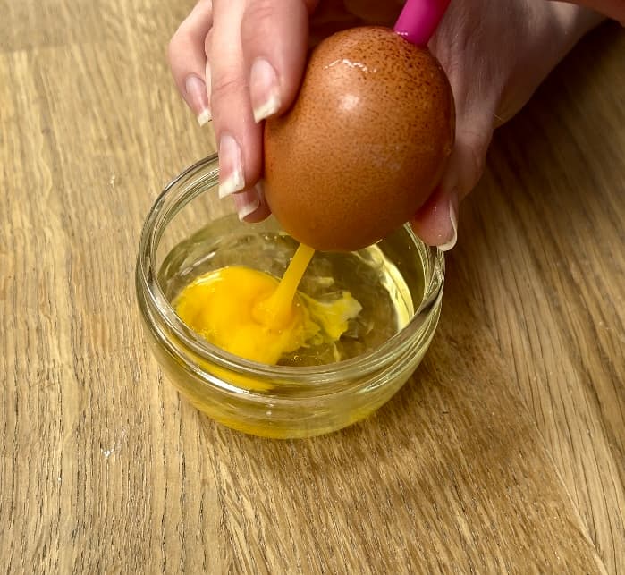 image shows yolk being removed from egg with straw.