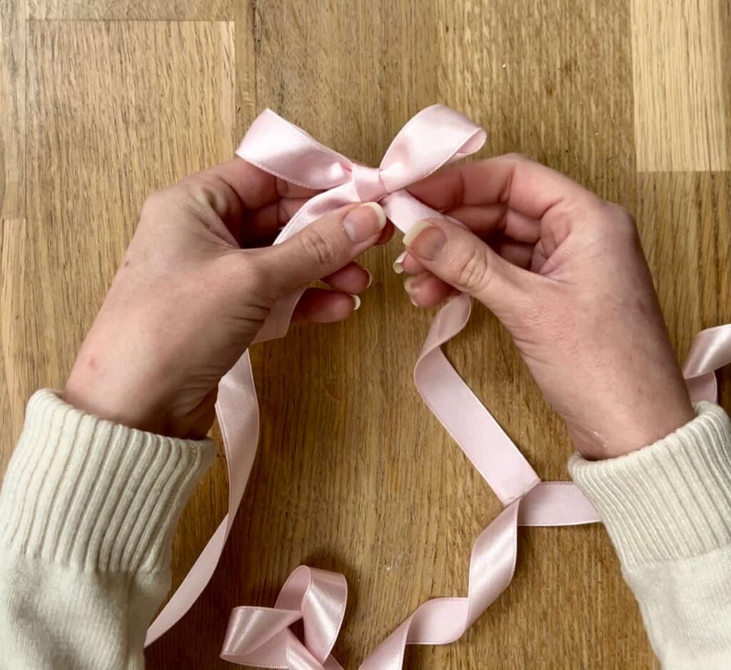 image shows tying a pink ribbon.