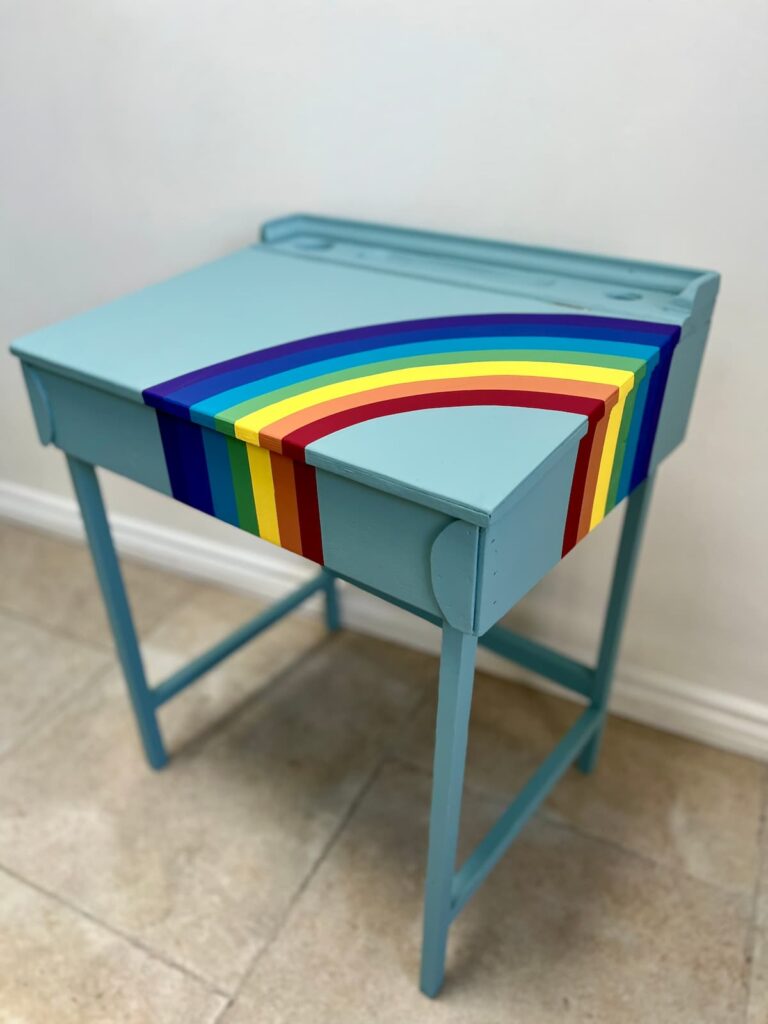 image shows painted blue desk with rainbow.