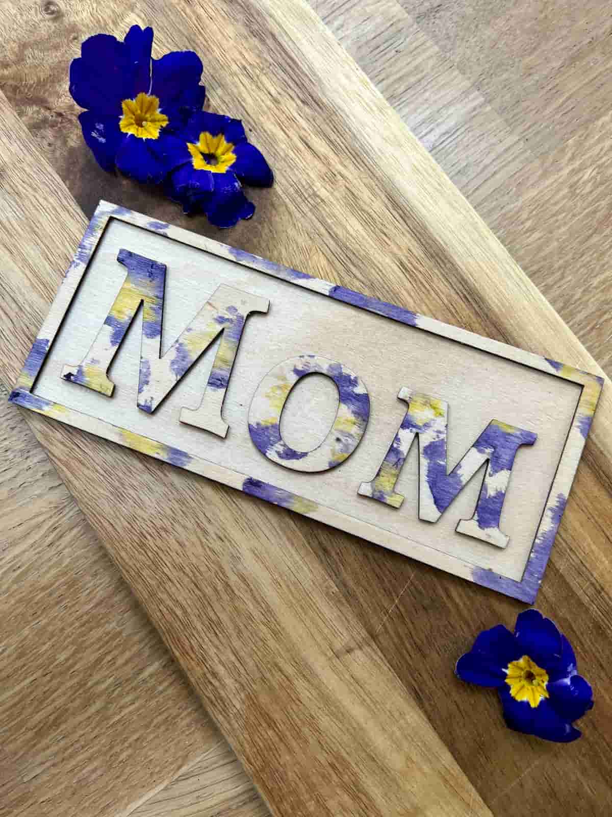 image shows wooden magnet with mom letters and pansies