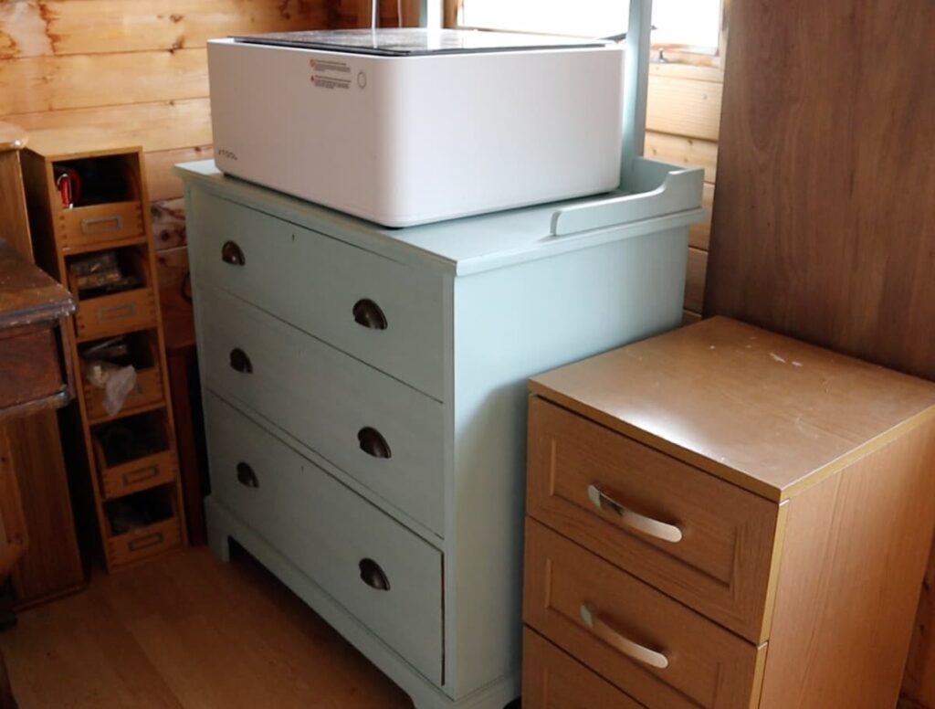 image shows green chest of drawers in shed with xtool machine on top.