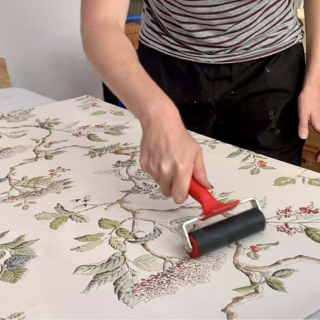 Using a brayer to smooth out the wallpaper after glueing 