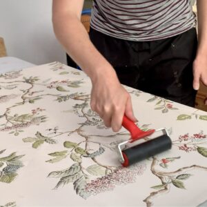 Using a brayer to smooth out the wallpaper after glueing