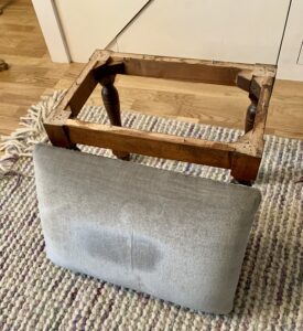 The footstool with the base and cushion separated -  black wax on furniture 