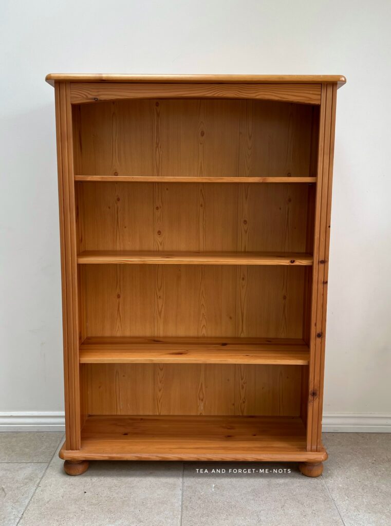 image shows pine bookshelf before makeover.