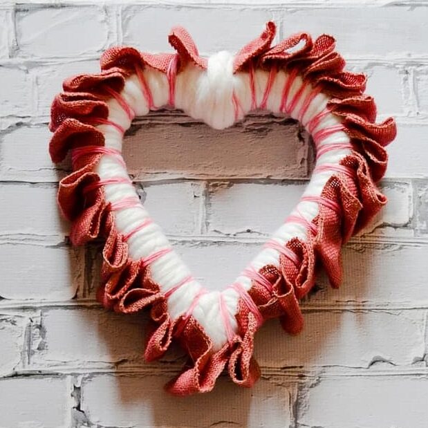 image shows heart wreath decorated with yarn and burlap.
