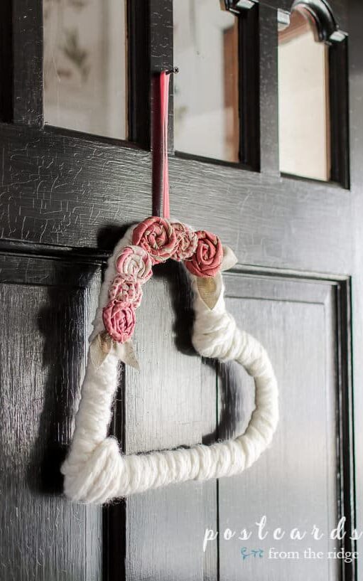 image shows white heart wreath on black door.