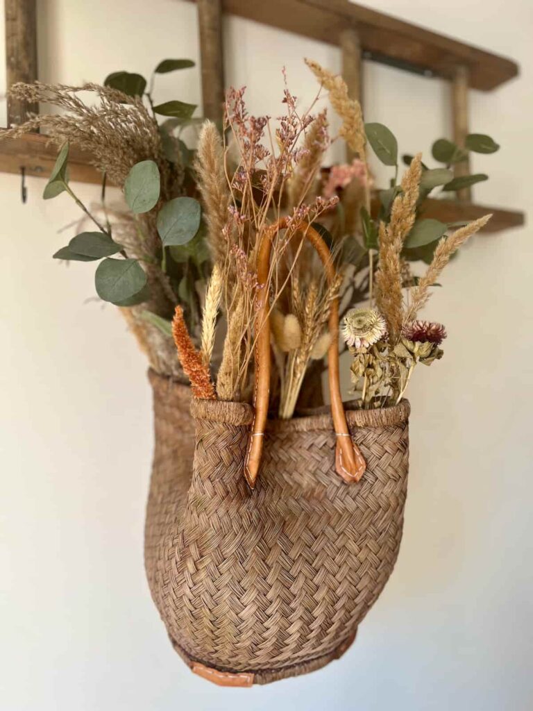 image shows stained basket with faux florals inside.