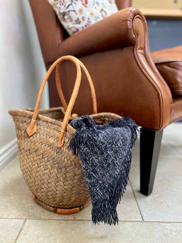 image shows stained basket with blanket next to a chair.